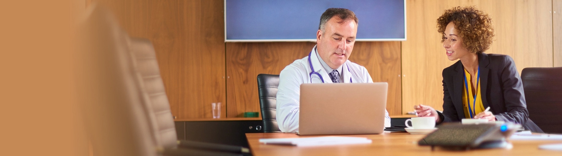 doctor with computer conferring with woman in business suit