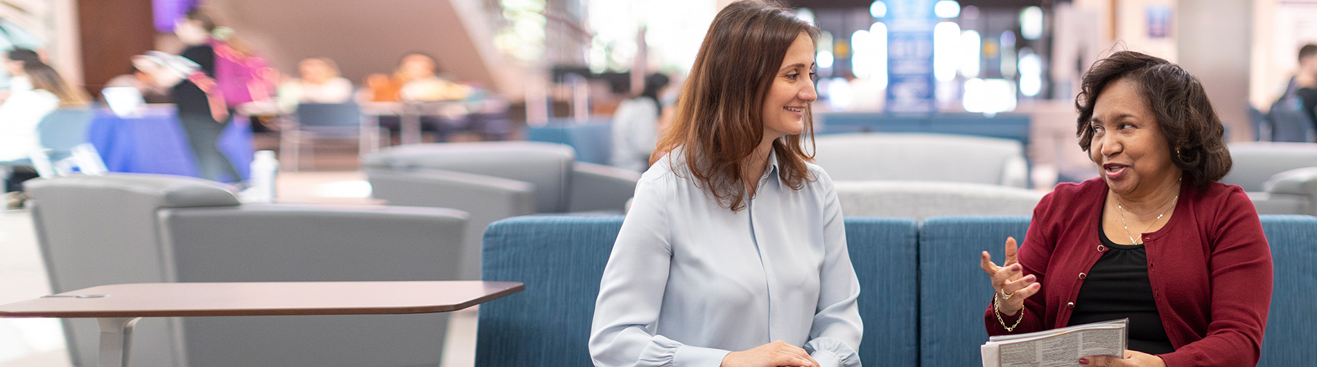 two women in business casual attire discussing a text