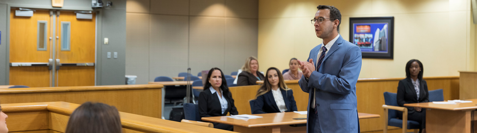 man in business suit talking to jury in courtroom