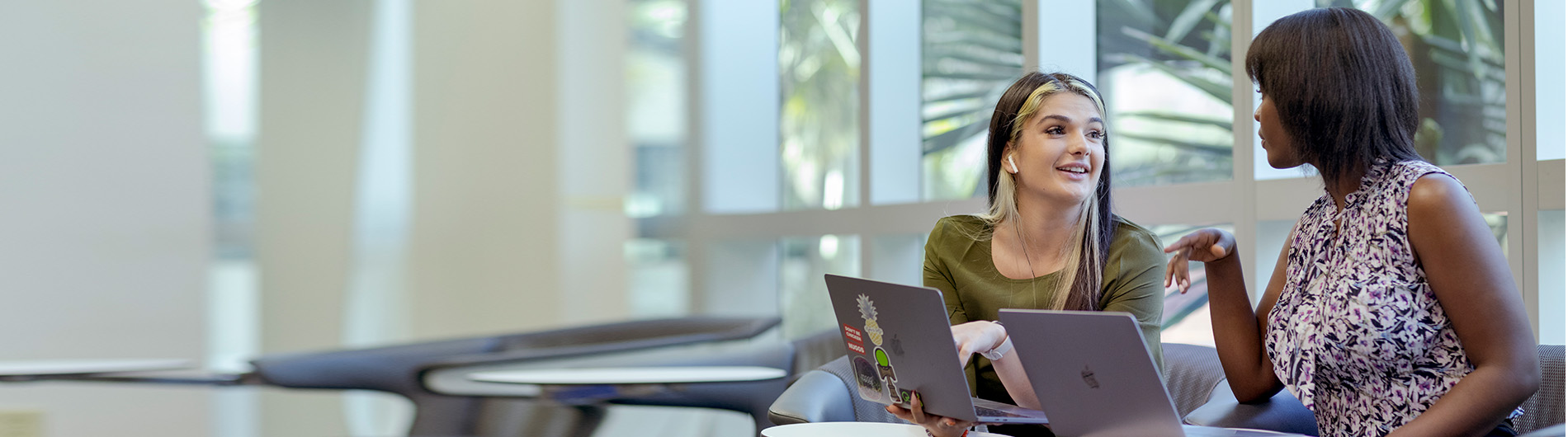 two young women in front of computers having discussion