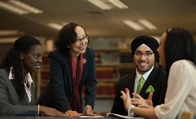 Diverse group of people in professional attire, sitting and chatting in a library