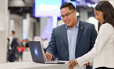 graduate students in professional attire at a conference looking at a laptop