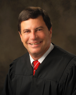 Portrait of a smiling judge in formal attire on a brown background