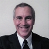 Portrait of a smiling man in a black suit and black tie on a white background