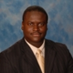 Portrait of a man in a pinstripe black suit and gold tie on a blue background