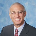 Portrait of a smiling man in a gray suit and red and white tie on a blue background