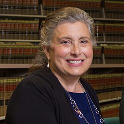 Portrait of a smiling woman with bookshelves lined with encyclopedias in the background