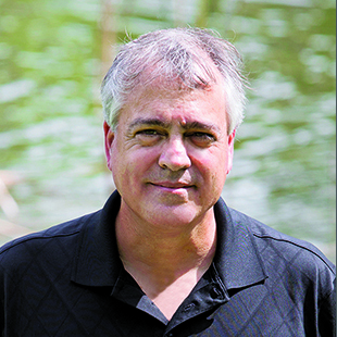 Portrait of a man in a black shirt with a lake in the background