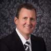 Smiling man in black suit on a gray patterned background