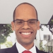 Portrait of a smiling man in a suit and red tie with buildings in the background