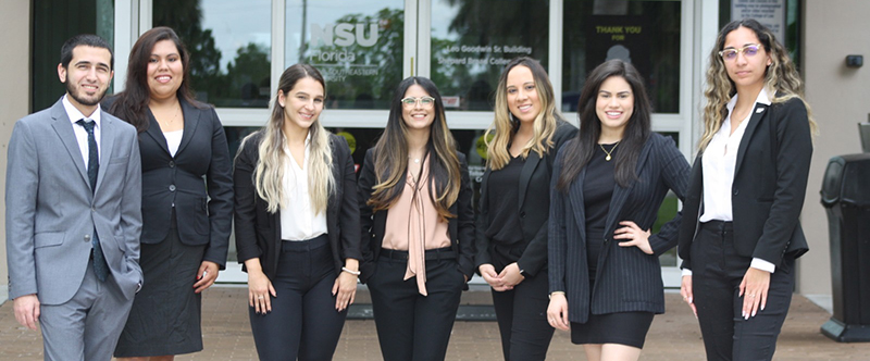 Group of students in professional attire standing together in front of a building