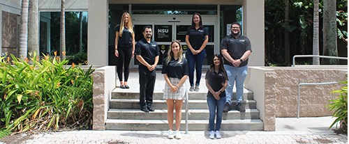 Group picture of six students standing in front of an NSU Law building