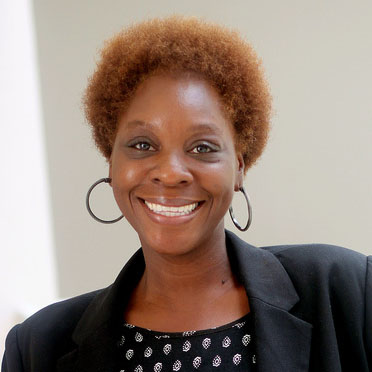 Portrait of a smiling woman in a black suit standing indoors