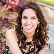 Portrait of a smiling woman outdoors with shrubbery in the background