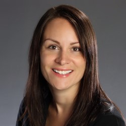 Portrait of a smiling brunette woman in a black suit on a gray background