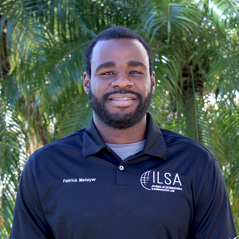 Portrait of a smiling man in a navy polo shirt with plants in the background