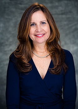 Portrait of a smiling woman in a blue blouse on a gray background