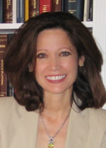 Portrait of a smiling woman standing in front of a bookcase lined with encyclopedias