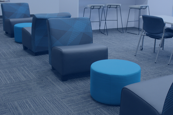 Gray and blue chairs and white tables in a room with gray carpet