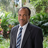 Portrait of a man in a suit with plants and grass in the background