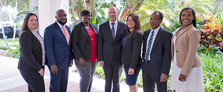 Group of professionally-dressed adults standing together in a half circle and smiling