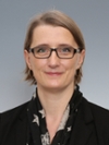 Portrait of a smiling woman wearing black and glasses on a gray background